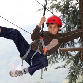 Immagine di un bambino che si diverte su un percorso avventura tra gli alberi