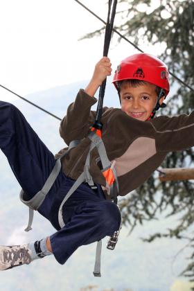 Immagine di un bambino che si diverte su un percorso avventura tra gli alberi